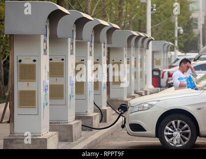 Peking, China. 14 Okt, 2018. Ein chinesischer Mann wartet auf seine chinesischen elektronische Fahrzeug (EV) - in einem der vielen Ladestationen in Peking am 14. Oktober 2018 mit Strom versorgt werden. China ist der größte Automobilmarkt der Welt, und seine Regierung hat der Welt größter Verfechter der elektrischen Autos geworden. China entfallen 40 Prozent aller elektrischen Autos weltweit verkauft. Quelle: Todd Lee/ZUMA Draht/ZUMAPRESS.com/Alamy leben Nachrichten Stockfoto