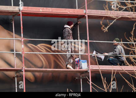 Berlin, Deutschland. 21 Feb, 2019. Zwei Spritzen auf dem Gerüst füllen Sie das riesige Wandbild auf das Haus des East Side Hotel. Das sind die Hände von Mona Lisa. Quelle: Annette Riedl/dpa/Alamy leben Nachrichten Stockfoto