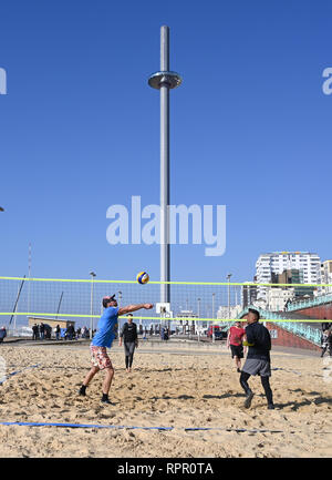 Brighton, East Sussex, UK. 23. Feb 2019. Beach Volleyball Spieler auf Brighton Seafront genießen Sie die schönen sonnigen und ungewöhnlich warmen Wetter für die Zeit des Jahres, mit einem Server einrichten Prognose in den nächsten Tagen in ganz Großbritannien: Simon Dack/Alamy Live News, um fortzufahren Stockfoto