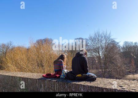 Paar genießen die ersten Sonnenstrahlen an der alten Wehrmauer in der Innenstadt von Maastricht Stockfoto
