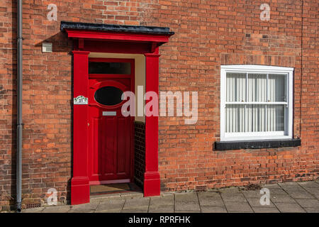 Nahaufnahme von 1950 - 60 die rote Tür mit ovalen Fenster und Portal auf einem roten gemauerte Haus in Markt, Tickhill in der Metropolitan Borough von Don Stockfoto