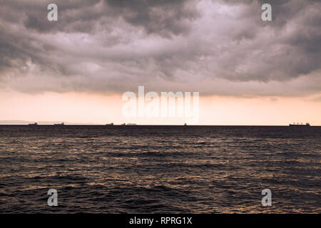 Gewitterwolken über dem Meer. Silhouetten der Schiffe am Horizont. Dramatische Himmel, cloudscape. Adria. Italien. Seascape. Bügeleisen Meeresoberfläche, gelbes Licht. Stockfoto