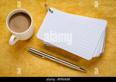 Stapel leer index Karten mit einer Tasse Kaffee und einem Stift gegen gelbe strukturiertes Papier Stockfoto