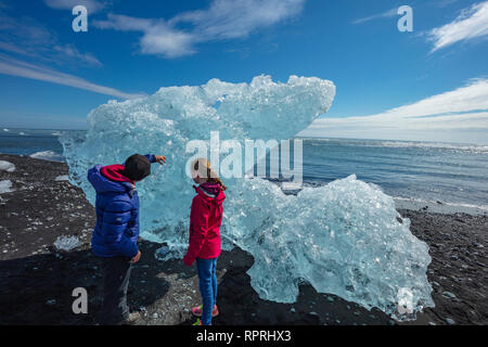 Menschen Prüfung Eisberge auf Breidamerkursandur schwarzer Sandstrand, unter Jokulsarlon ist. Sudhurland, South East Island. Stockfoto