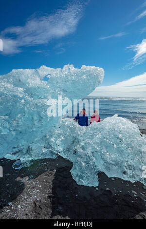 Menschen Prüfung Eisberge auf Breidamerkursandur schwarzer Sandstrand, unter Jokulsarlon ist. Sudhurland, South East Island. Stockfoto