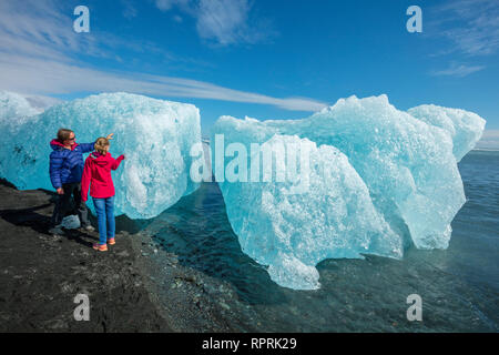 Menschen Prüfung Eisberge auf Breidamerkursandur schwarzer Sandstrand, unter Jokulsarlon ist. Sudhurland, South East Island. Stockfoto