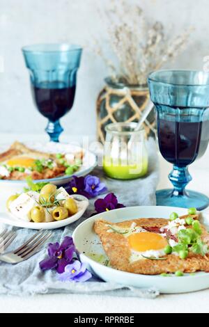 Bretonische traditionelle Pfannkuchen aus Buchweizenmehl mit Schinken, Käse, Ei, Feta, grüne Erbsen und grüne Butter. Frühstück von Buchweizen dünne Pfannkuchen wi Stockfoto