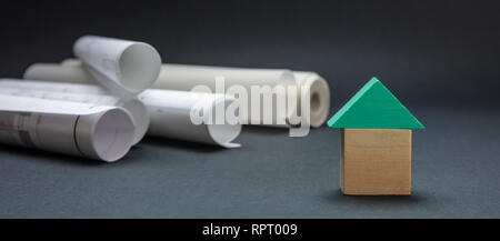 Immobilien Konzept. Kleines Haus mit Dach Modell und Projektentwürfe auf schwarzem Hintergrund, Banner Stockfoto