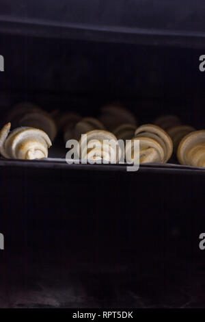 Frisch gebackene Croissants mit Schokolade auf einem Backblech in den Ofen Stockfoto