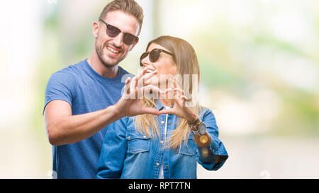 Junges Paar in Liebe Sonnenbrille tragen über isolierte Hintergrund in der Liebe mit Herz und mit Hand lächelnd. Romantische Konzept. Stockfoto