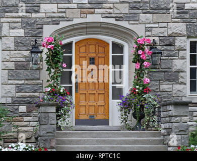 Elegante Holz- Vordertür umgeben von Blumen Stockfoto