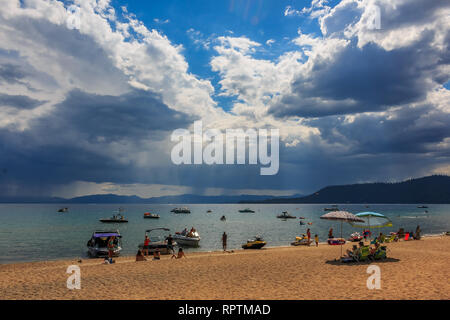 Sonnenstrahlen über dem Wasser über Lake Tahoe in Kalifornien, USA, gesehen, Touristen entspannen am Strand und Boote im Wasser Stockfoto