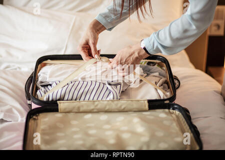 Tourismus, Geschäftsreise, Personen und Gepäck Konzept - aus der Nähe von weiblichen Händen packen Dinge für eine neue Reise im Koffer. Stockfoto