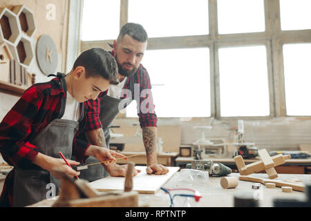 Neugierige kleine Junge Klassen der Tischlerei aus berühmten WOODWORKER. Hobby wächst in der Arbeit von Berufung. Stockfoto