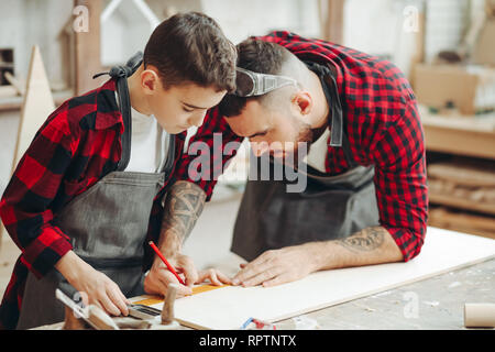 Neugierige kleine Junge Klassen der Tischlerei aus berühmten WOODWORKER. Hobby wächst in der Arbeit von Berufung. Stockfoto