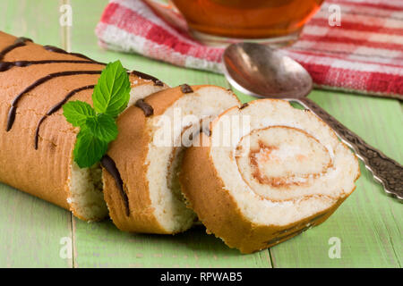 Keks swiss Roll am grünen Holz- Hintergrund Stockfoto