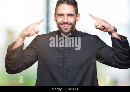 Junge christliche Priester über isolierte Hintergrund Lächeln zeigte mit beiden Händen, Finger, tolle Idee oder gedacht, gutes Gedächtnis zu Kopf Stockfoto