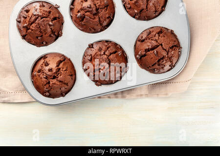 Eine Nahaufnahme der Chocolate Chip Muffins in einer Backform, Schuß von oben auf einen hellen Hintergrund mit einem Platz für Text Stockfoto