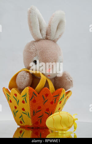 Ein Plüsch Spielzeug Bunny in einem Osterkorb mit Gelb Osterei Stockfoto