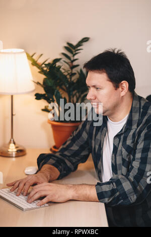Porträt eines jungen männlichen Schriftsteller arbeiten im Home Office, mit einem Computer. Bild vertikal. Stockfoto