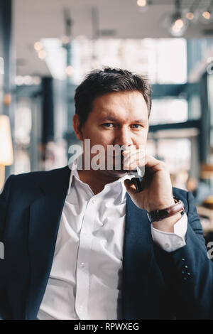 Close-up Portrait von gut aussehende junge Unternehmer mit hohem Selbstwertgefühl, sitzen in einer Bar, posieren für die Kamera. Bild vertikal mit Platz für Text Stockfoto