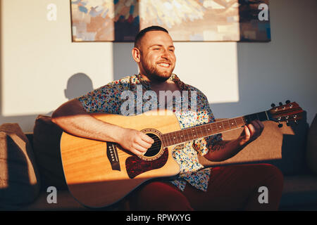 Schöner Mann spielen akustische Gitarre zu Hause Stockfoto