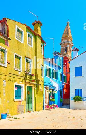 Straße und der schiefe Kirchturm der St. Martinskirche im Hintergrund in Insel Burano, Venedig, Italien Stockfoto