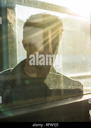 Ein stattlicher Mann hinter Glas im Freien in Telefonzelle Stockfoto