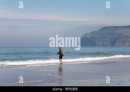 Mann angeln im Meer am Strand von cattersty Sands, Skinningrove, North Yorkshire, England. Stockfoto