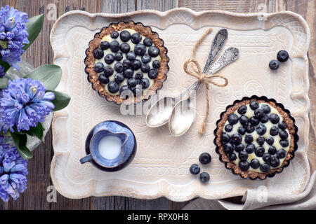 Draufsicht auf Vollkorn blueberry Torten mit Vanille Creme auf einem keramischen Fach auf Holz Stockfoto