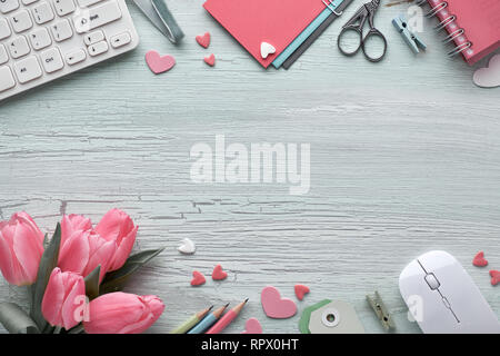 Frühling flach mit Tastatur, Maus, rosa Tulpen, stationär, Grußkarten, dekorative Herzen und Copy-Platz in der Mitte. Vorbereitung für eine b Stockfoto