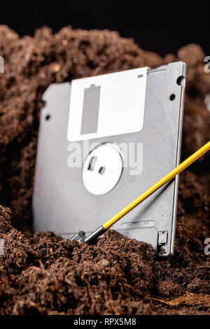 Die Diskette ist halb in die Erde eingegraben, neben einer Schaufel Stockfoto