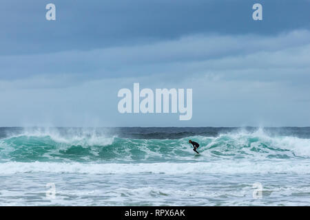 Männliche Surfer im Taucheranzug Reiten eine Welle auf Dalmore Strand, Insel Lewis, Äußere Hebriden, Schottland Stockfoto