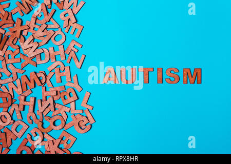 Das Wort Autismus aus Holz Buchstaben auf blauem Hintergrund. Das Problem ist bei der Sozialisation, Kommunikation Stockfoto