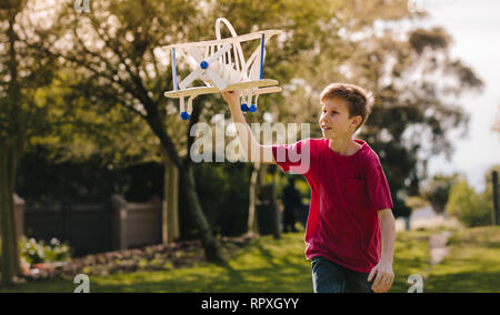 Junge spielt mit einem Spielzeug Flugzeug in den Park an einem Sommertag. Junge läuft mit einem Spielzeug Flugzeug im Freien. Stockfoto