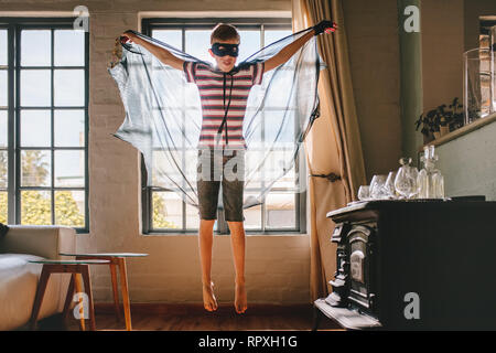 Junge mit Karneval Kostüm, das Tragen von Bat-förmigen Cape und Augenmaske. Junge spielt in Bat Kostüm zu Hause. Stockfoto