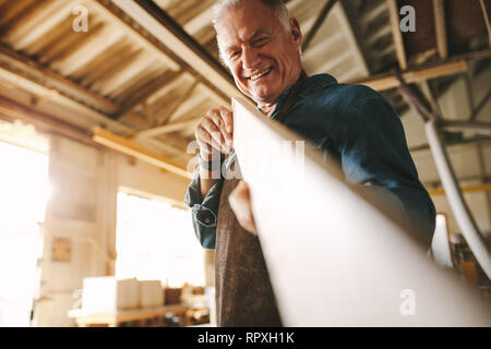 Senior Tischler prüfen, wenn das Board ist flach und sogar. Handwerker in Holz, prüfen Sie auf Geradheit während der Vorbereitung Teil für Möbel. Stockfoto