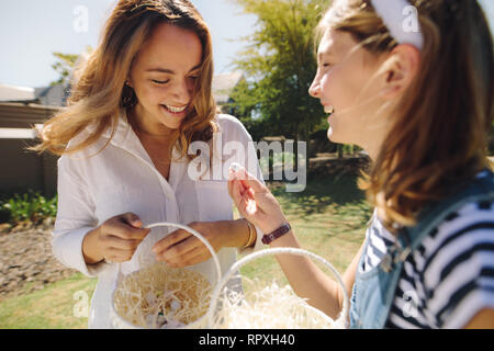 Lächelnde Frau mit ihrer Tochter stehen im Freien holding Osterei Körbe. Happy girl Holding ein Osterei süße stehen mit ihrer Mutter im Freien Stockfoto