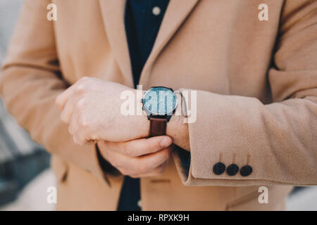 Close-up Detail der Accessoire für Männer - ein Mann, der die Zeit und Spannen des Riemens auf seine Armbanduhr. Stockfoto