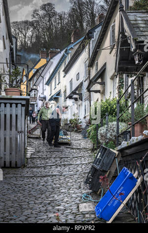 Zwei Männer liefern Winter versorgt von einem traditionellen Schlitten für die Bewohner in der High Street in Clovelly in North Devon. In einen steilen Hang, Sle Stockfoto