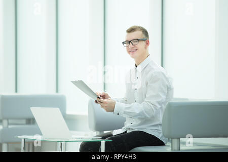 Mitarbeiter des Unternehmens liest einen Business Document im Büro Lobby sitzen Stockfoto