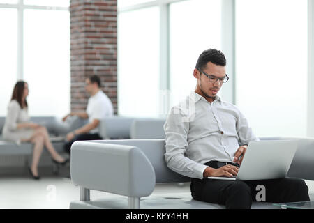 Junge Mann arbeitet auf einem Laptop in der Lobby Stockfoto