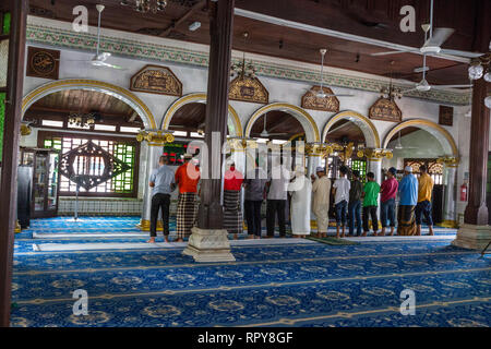 Männer beobachten Mittag Gebete, die Kampung Kling Moschee Masjid Kampung Kling, Melaka, Malaysia. Stockfoto