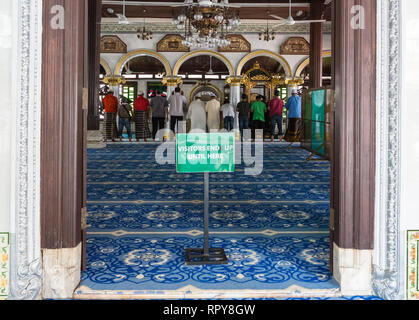 Männer beobachten Mittag Gebete, die Kampung Kling Moschee Masjid Kampung Kling, Melaka, Malaysia. Zeichen fordids weiterer Eintrag von nicht-Muslime. Stockfoto