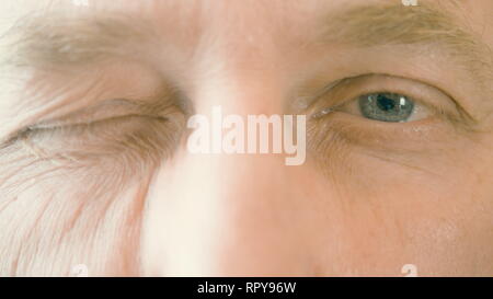 Gesicht und Augen der älteren Mann mit einem Augenzwinkern und Blick in die Kamera. Close up männliche Augen Stockfoto