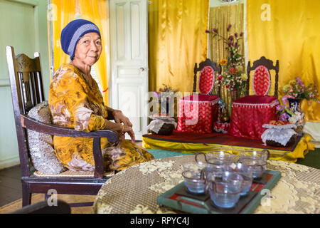 Villa Sentosa, Enkelin des ursprünglichen Besitzers, Melaka, Malaysia. Hochzeitsstühle im Hintergrund. Beispiel eines wohlhabenden malaiischen Hauses aus dem frühen 20. Jahrhundert. Stockfoto