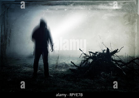 Eine unheimliche Silhouette eines einsamen hooded Abbildung in einem Feld mit einem dunklen, gruseligen verschwommen abstrakt, grunge Effekt bearbeiten. Stockfoto