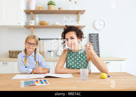 Mutter und Tochter Malerei zusammen zu Hause in der Küche mit Pinsel und Wasserfarben Stockfoto