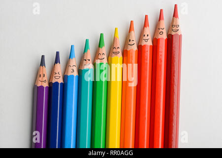Reihe der Buntstifte mit lustigen Lächeln auf weißem Hintergrund. Regenbogen und andere Gefühle. Stockfoto