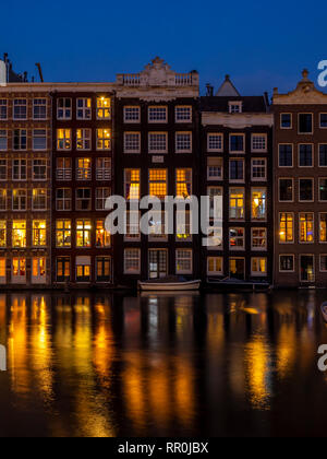 Historische Gebäude am Damrak Kanal in der Mitte des wunderschönen Amsterdam bei Nacht. Ligts der Gebäude sind in den Kanal wider. Stockfoto